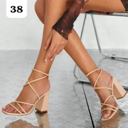 Sandalias de tacón alto en tono beige con diseño envolvente y sofisticado. 