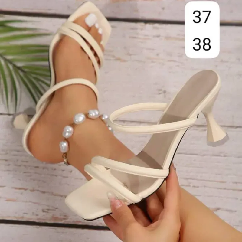 Sandalias de tacón alto en tono crema con diseño moderno y delicado.