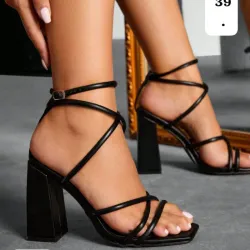 Sandalias negras de tacón alto con diseño envolvente y moderno. 
