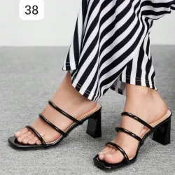 Sandalias negras de tacón cuadrado con diseño moderno y estilizado.
