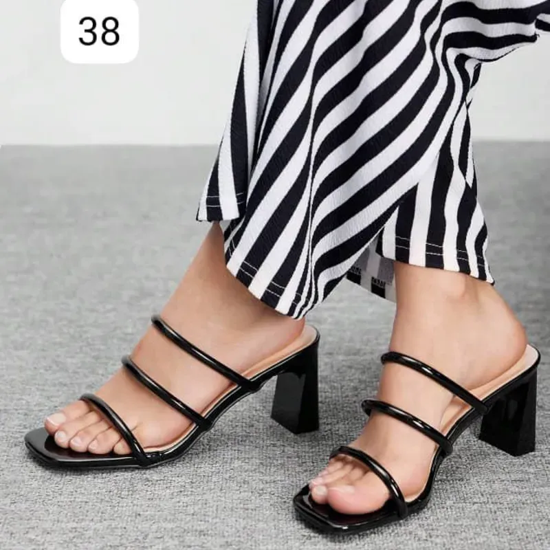 Sandalias negras de tacón cuadrado con diseño moderno y estilizado.