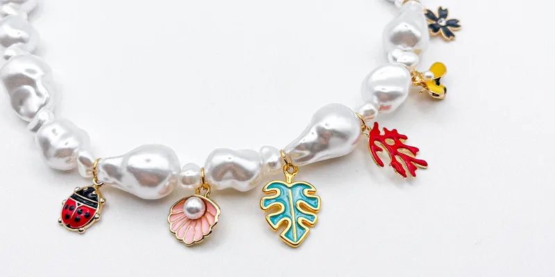 Collar con perlas artificiales y dijes con enchape 