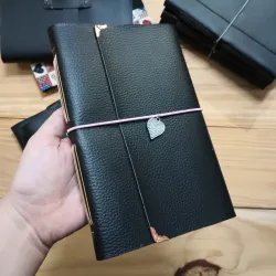 Cuaderno de vinil negro con elástico rosado y colgante de corazón 