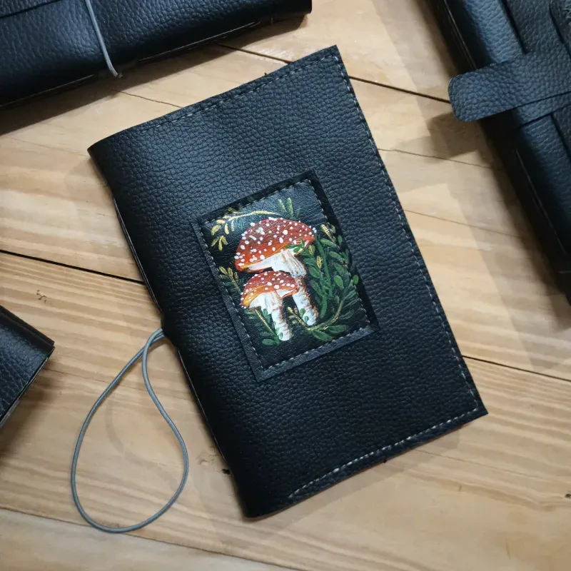 Cuaderno de vinil negro con pintura de hongos